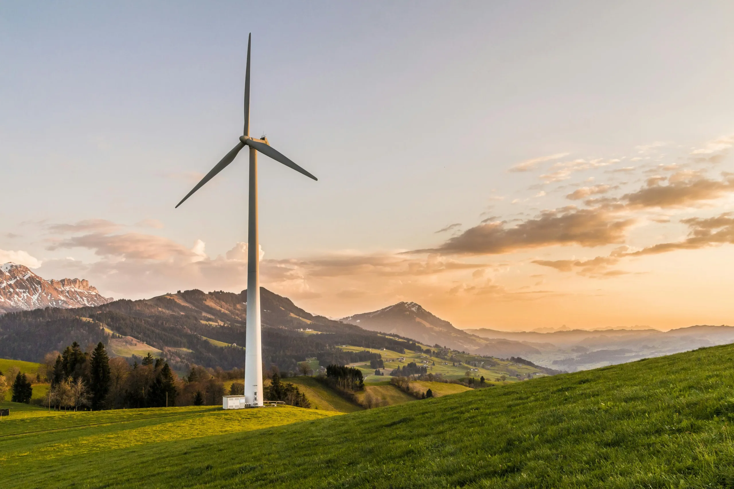 Wind turbine with mountains in the background and water in the distance, likely in California.