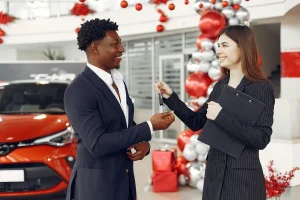 A small business owner is purchasing a vehicle from a dealership near Christmas time, as there are decorations about the dealerlship.