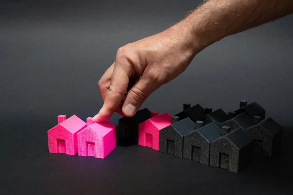 Plastic models of houses are lined up in rows, mostly black and a few pink ones.