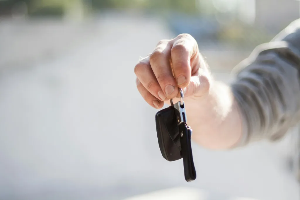 Hands dangling car keys for a new business automobile.
