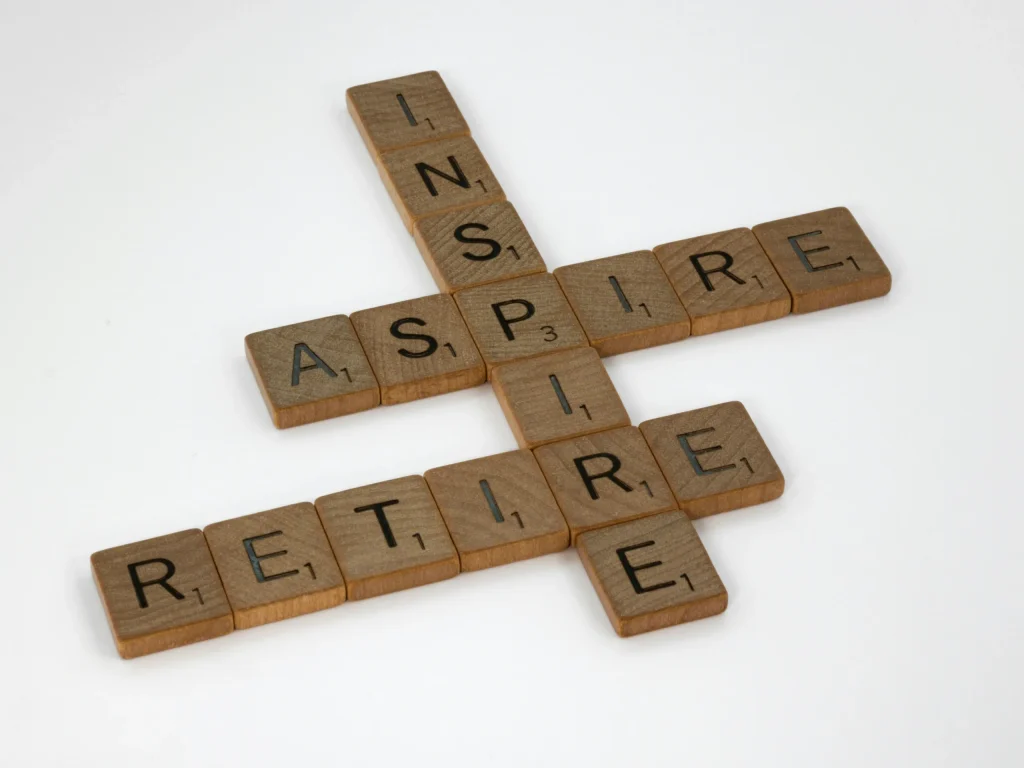Scrabble tiles over a white background that form four words, intersecting. They read, "inspire, aspire, retire".