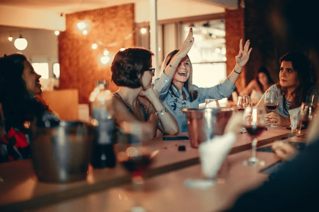 Restaurant patrons enjoying a diner night. One woman has her arms in the air with excitement. 