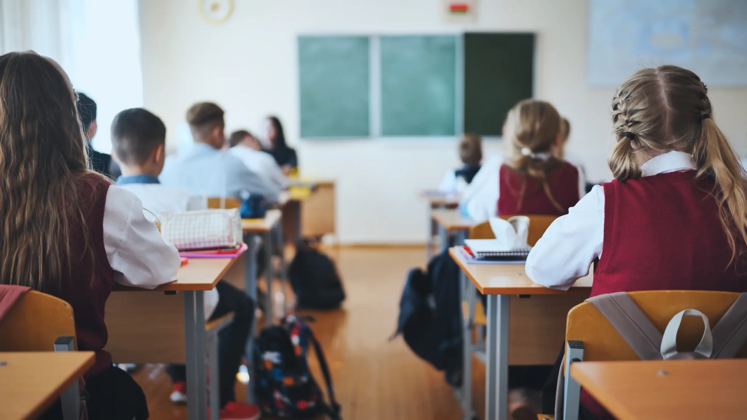 private school accountant taken from the back, students are in a classroom seated behind desks with a row straight down the middle
